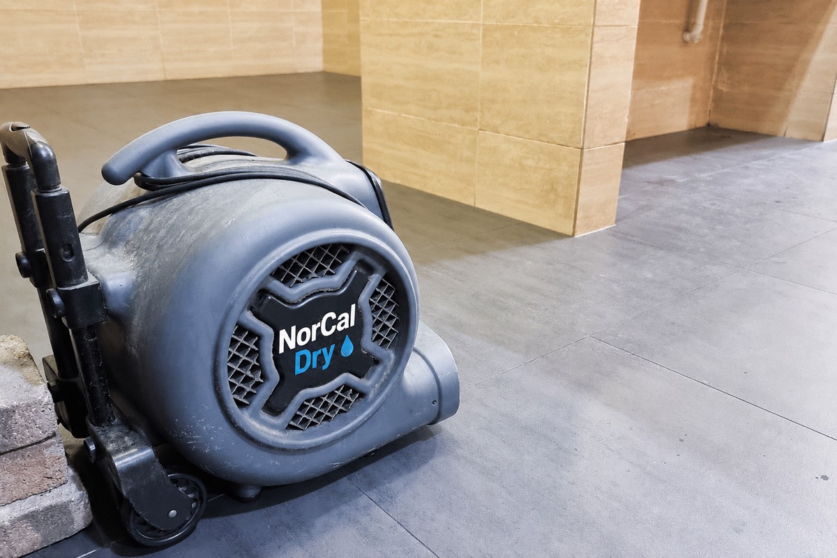 NorCal Dry industrial air mover drying a tiled floor after water damage